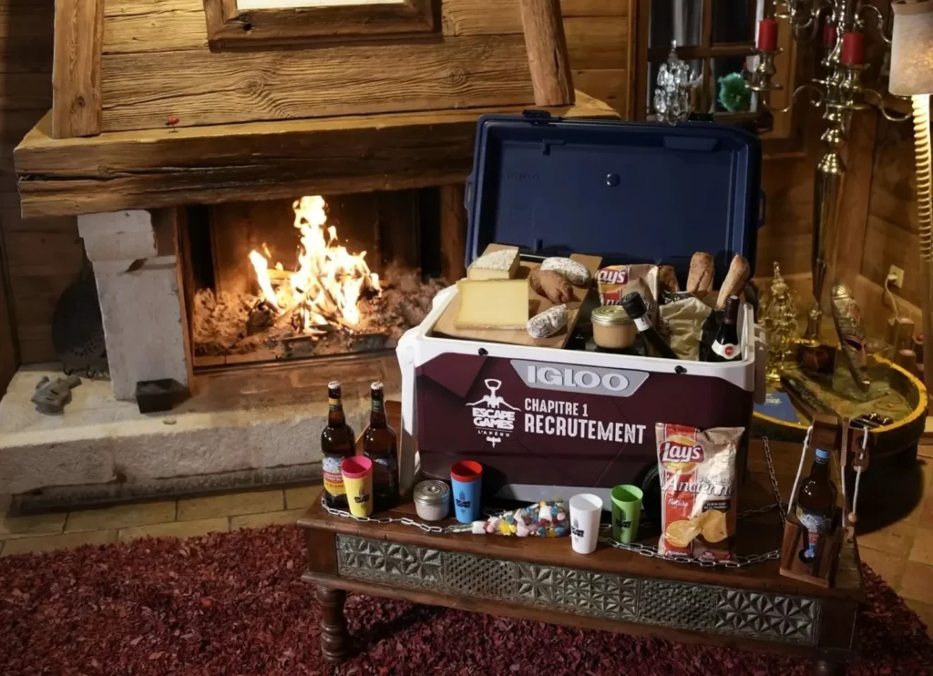Glacière Escap'Apéro Chapitre 1 remplie de boissons et snacks au coin du feu - La Grande Évasion